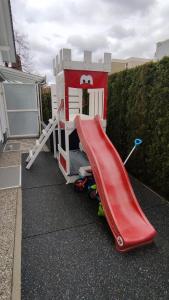 uma casa de brincar com um escorrega vermelho em Ferienwohnung Krause em Augsburg
