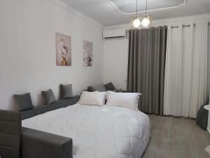 a bedroom with a large white bed and a couch at Alis Apartaments in Himare