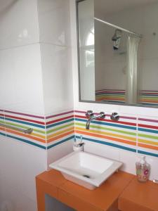 baño con lavabo y pared a rayas de arco iris en Casa en club privado loma verde en Zelaya