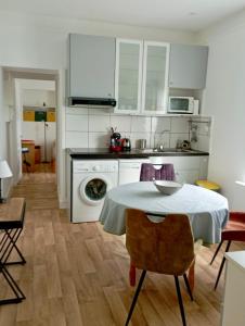 uma cozinha com uma mesa e uma cozinha com armários brancos em Appartement proche de la plage - wifi, bien agencé em Asnelles