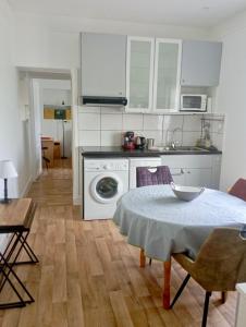 a kitchen with a table and a kitchen with white cabinets at Appartement proche de la plage - wifi, bien agencé in Asnelles