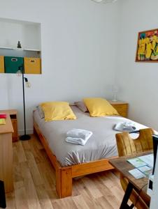a bedroom with a bed with yellow pillows and a table at Appartement proche de la plage - wifi, bien agencé in Asnelles