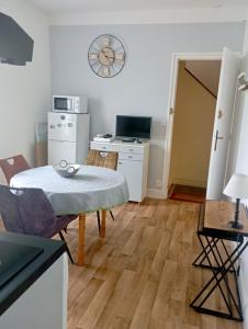 a room with a table and a kitchen with a clock on the wall at Appartement proche de la plage - wifi, bien agencé in Asnelles