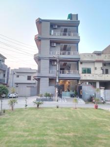 um edifício alto com um jardim de relva em frente em Dove Inn Family Residency Johar Town em Lahore