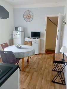 uma sala de estar com uma mesa e um relógio na parede em Appartement proche de la plage - wifi, bien agencé em Asnelles