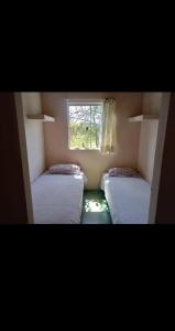 two beds in a small room with a window at Casa Flor do Cerrado Luz do caminho in São João da Aliança