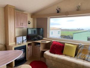 a living room with a couch and a tv and a window at Caravan SK 110 in Leven