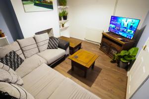 a living room with a couch and a television at 3 Bedroom home by Ipswich docks. in Ipswich
