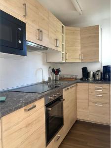 a kitchen with wooden cabinets and a stove top oven at Ferienwohnung Schwarzwaldtraum - 2Zi - Feldberg in Hinterfalkau