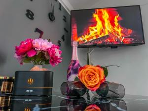 a table with flowers and a tv with a fire at Apartment Sova or Deluxe room 33 in Bled