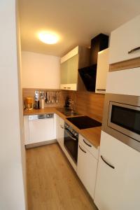 a kitchen with white cabinets and a sink and a stove at Kurhotel Schluchsee App 1003 - Ferientraum - mit Indoorpool, Sauna, Schluchsee in Schluchsee