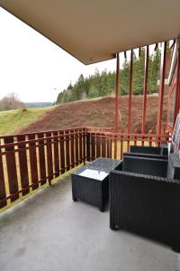 a porch with chairs and a table and a fence at Kurhotel Schluchsee App 1003 - Ferientraum - mit Indoorpool, Sauna, Schluchsee in Schluchsee +16 photos