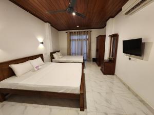 a bedroom with two beds and a flat screen tv at Regno Villa the Infinity by Nflix in Panadura