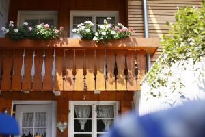 uma varanda de madeira com flores numa casa em Ferienhaus im Gässle, Kirchzarten, Dreisamtal em Kirchzarten