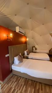 two beds in a room with red walls at Wadi rum Gory camp in Disah