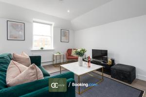 a living room with a green couch and a table at Elegant 2 Bed Harbour Front Flat By OC House Short Lets & Serviced Accommodation Gillingham, Ramsgate, Folkestone With Balcony in Kent
