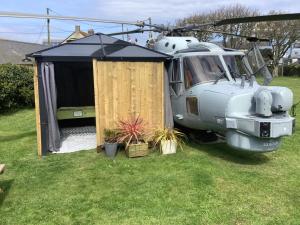 a helicopter parked in a field with a tent at Haelarcher Helicopter Glamping in Helston