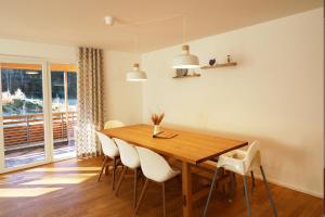 a dining room with a wooden table and white chairs at Haus Wiesenquelle - Fewo 10 "Uff'm Berg", Feldberg in Rinken