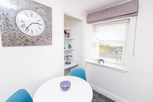 a white room with a white table and a clock on the wall at Seaview Cottage Central Dundee in Dundee