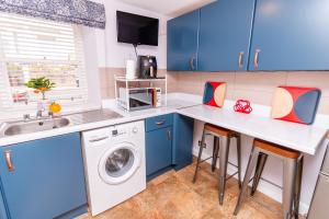 a kitchen with blue cabinets and a washer and dryer at Seaview Cottage Central Dundee in Dundee