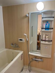 uma casa de banho com uma banheira e um espelho. em N's Home-南名古屋駅一軒家ルームシェア-4 em Nagoia