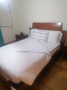 een groot bed met witte lakens en kussens bij esthela home 2 in Funchal