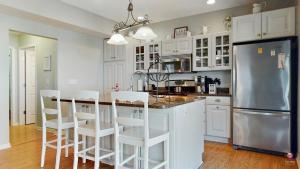 a kitchen with white cabinets and a stainless steel refrigerator at Charming Cottage Prime Location 3BR in South Haven
