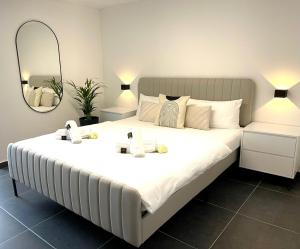 Cette chambre comprend un grand lit blanc et un miroir. dans l'établissement Stilvolles Designappartment mit Terasse & Garten im idylischem Bindlach, à Bindlach