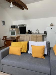 a gray couch with yellow pillows in a kitchen at La Requeyrie in Montignac