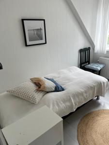 ein weißes Schlafzimmer mit einem Bett und einem Stuhl in der Unterkunft Holbæk. Byhus med fjordudsigt, og 5 min. til bymidten in Holbæk