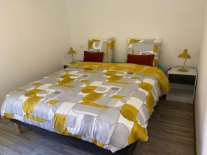 a bedroom with a bed with a yellow and white comforter at La Requeyrie in Montignac