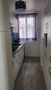 a kitchen with a sink and a window with purple curtains at Beach Front Apartment Eljocri in Capbreton