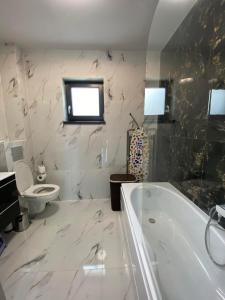 uma casa de banho com uma banheira branca e um WC. em Casa Bellevue em Bacau