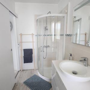 a white bathroom with a shower and a sink at Beach Front Apartment Eljocri in Capbreton