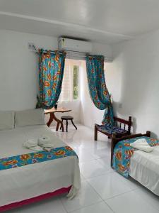 a bedroom with two beds and a table and a window at Pousada Sol de Amaro in Santo Amaro