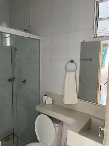 a bathroom with a toilet and a glass shower at Pousada Sol de Amaro in Santo Amaro