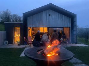 un grupo de personas sentadas alrededor de un pozo de fuego en un patio en Nouveau! Gîte contemporain entouré de 10 étangs, en Florennes