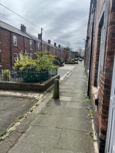 an empty street with brick buildings and a sidewalk at Quirky and Cosy Two Bed in Ferryhill Near Durham! in Ferryhill