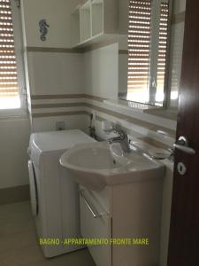 uma casa de banho com um lavatório e uma máquina de lavar roupa em Bilocali Approdo "Fronte Mare" e "Lato Strada" em Porto Cesareo