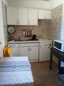 a kitchen with white cabinets and a table and a microwave at Little Hut do sul in São Brás de Alportel