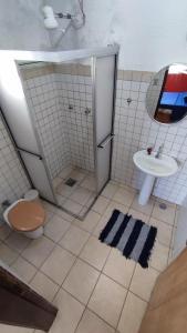 uma casa de banho com um chuveiro, um WC e um lavatório. em Maré Alta Hostel em Ubatuba
