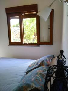 a bedroom with a bed with a mirror and a window at Little Hut do sul in São Brás de Alportel