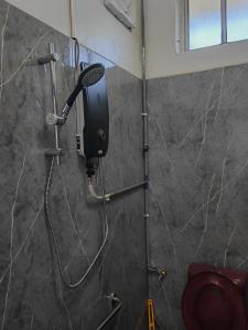 a shower in a bathroom with a hair dryer on a wall at Padang Serai Roomstay Family Suite Share Bathroom804 in Padang Serai