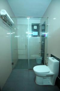 uma casa de banho com uma cabina de duche em vidro e um WC. em The Garudan Mountain View Residency em Kodaikanal