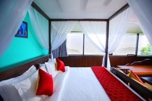 um quarto com uma cama com almofadas vermelhas e brancas em The Garudan Mountain View Residency em Kodaikanal
