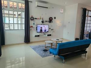 un salon avec un canapé bleu et une télévision dans l'établissement Padang Serai Roomstay Family Suite Share Bathroom804, à Padang Serai