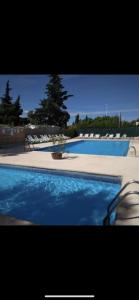 una gran piscina con agua azul y sillas en Mobilhome 6 personnes climatisé, en Villeneuve-lès-Maguelonne