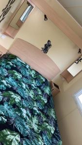 1 dormitorio con 1 cama con colcha verde en Mobilhome 6 personnes climatisé, en Villeneuve-lès-Maguelonne