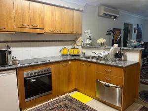 a kitchen with wooden cabinets and a stainless steel oven at Waldorf Hotel Apartments In Perth City Centre in Perth