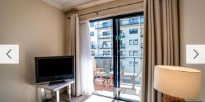 a room with a television and a window with a balcony at Waldorf Hotel Apartments In Perth City Centre in Perth